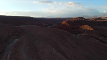 Aerial shot drone flies forward over viewpoint overlooking red desert mountains in Atacama at sunset