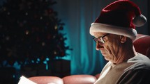 Elderly Man Reading Book On Christmas sofa in the house