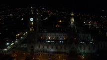 Aerial shot drone flies right in semicircle around the Basilica del Voto Nacional in Quito at night