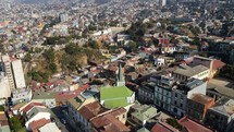 Aerial shot drone flies over church with green roof in middle of coastal city on sunny day