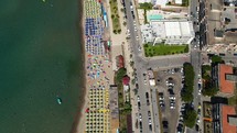 Aerial shot drone flies forward as camera pans up from beach to the city of Cefalu, Sicily, Italy