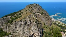 Aerial shot drone flies over La Rocca from south side to north, flying over the castle in Cefalu, Sicily, Italy