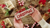 Hand Holding Merry Christmas text on presents background