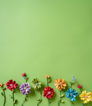 AI Generated Image. Flat lay of the paper colorful handmade flowers on a green background