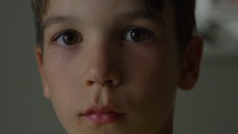 Young boy with worried look on face looks directly into camera - close up on face