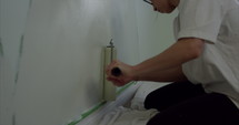 Woman painting childs bedroom walls accidentally paints over base boards - slow motion