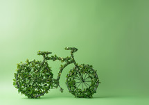 AI Generated Image. Model of bicycle made of leaves and plants against a green wall. Earth Day and Environmentalism concept