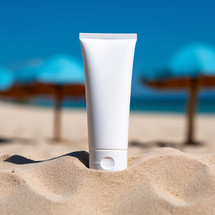 Blank empty white plastic tube. Sunscreen lotion on sandy beach