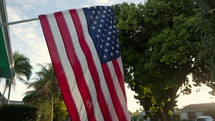 American flag hanging in front of house in quiet average american neighbourhood at sunset