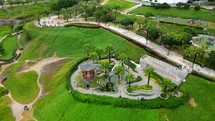 Aerial shot drone orbits to the rights around Chinese themed park on cliff overlooking coast