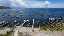 Aerial shot drone slowly flies to right over dock and beach of boat marina in port city