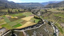 Aerial shot drone flies right as camera pans left over fields next to winding river in valley