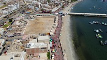 Aerial shot drone flies to right over marina with boats and pier surrounded by seabirds