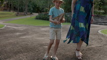 Young boy picks up paper airplane with his grandmother in park - generational love