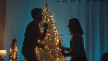 Silhouette of couple are dancing against the Christmas tree in the night