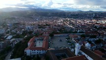 Aerial shot drone hovers over mirador plaza and large white church at top of hill overlooking city