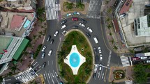 Aerial shot drone flies backwards over blue traffic roundabout at end of central park in downtown