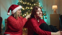 Girl is making hair style in Christmas time against the tree