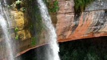 Aerial shot drone flies away from medium shot of middle of waterfall and slowly pans down to pool underneath