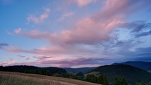 Colorful clouds at sunset over the hilly and forest landscape in the Carpathian hills
