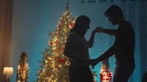 Silhouette of couple dancing against the Christmas tree in night
