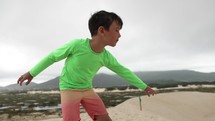 Young boy visualizing himself going down dunes on sand board gives thumbs up - ready to go