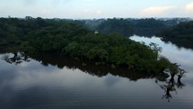 Aerial shot drone lowers over peninsula in black lagoon in middle of Amazon rainforest just before sunset