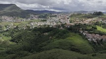 Drone flies over Brazilian countryside with rolling hills and small villages on a cloudy day