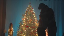 Silhouette of lovely couple are embracing against the Christmas tree