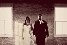 bride and groom standing in front of a brick wall