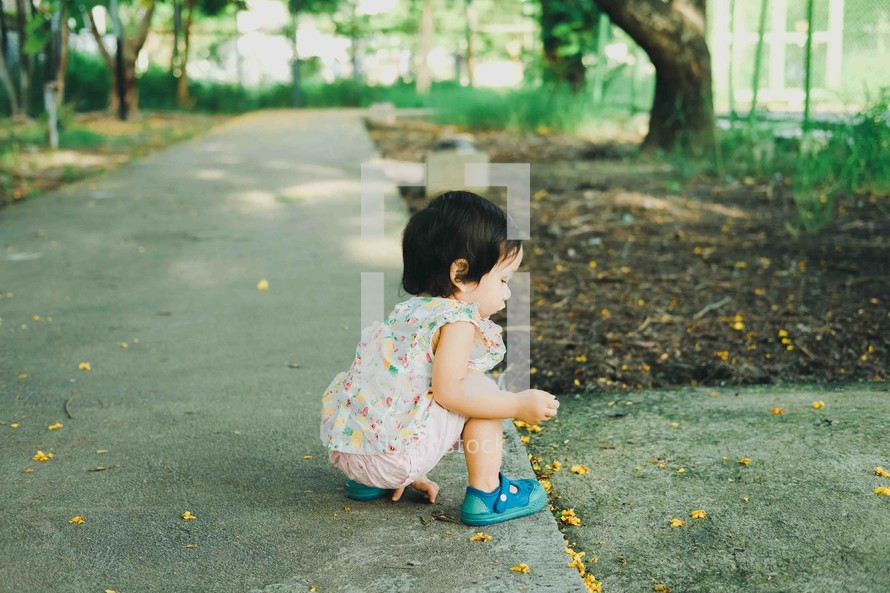curious toddler picking up a leaf 