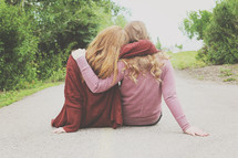 friends hugging sitting on a road 