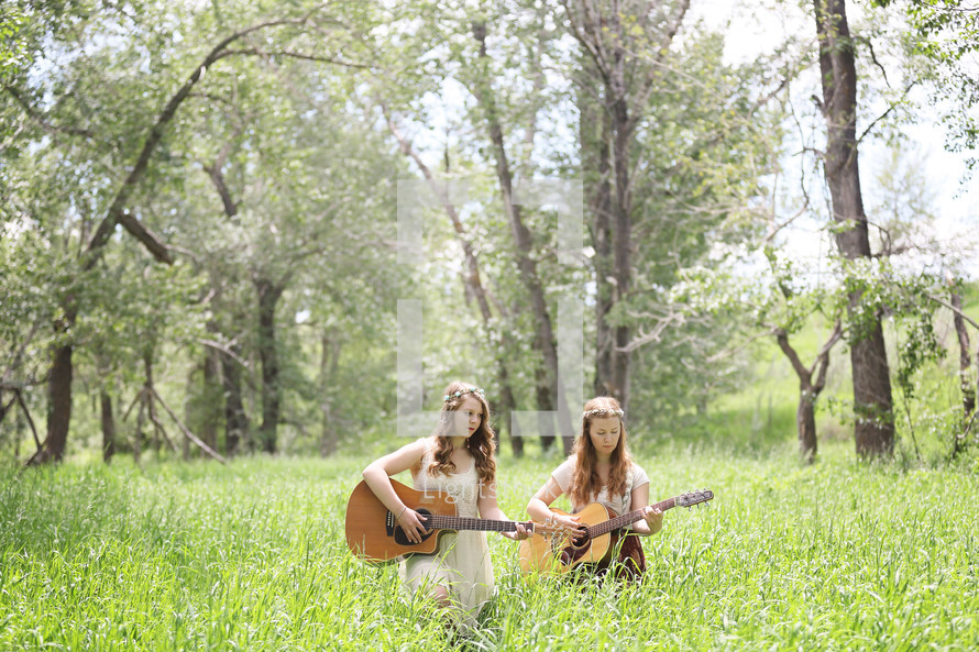 two girls singing and playing guitars outdoors