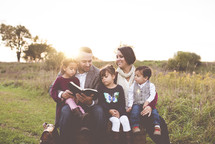 family reading a Bible together outdoors 