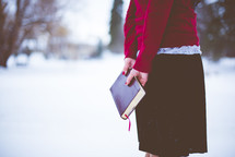 a woman holding a Bible standing in snow 