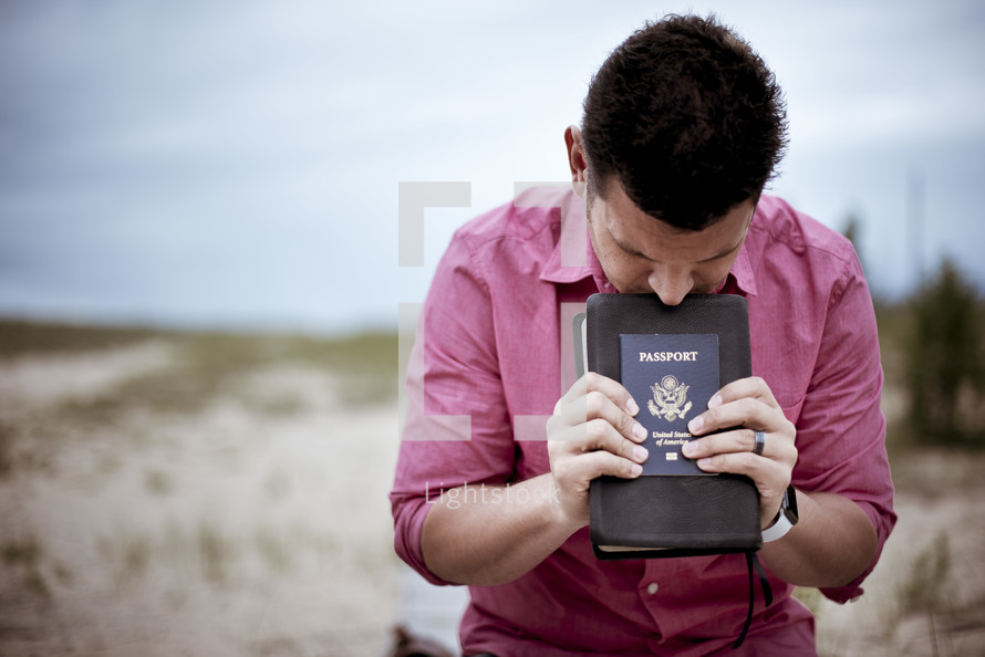 man holding passport and Bible praying 