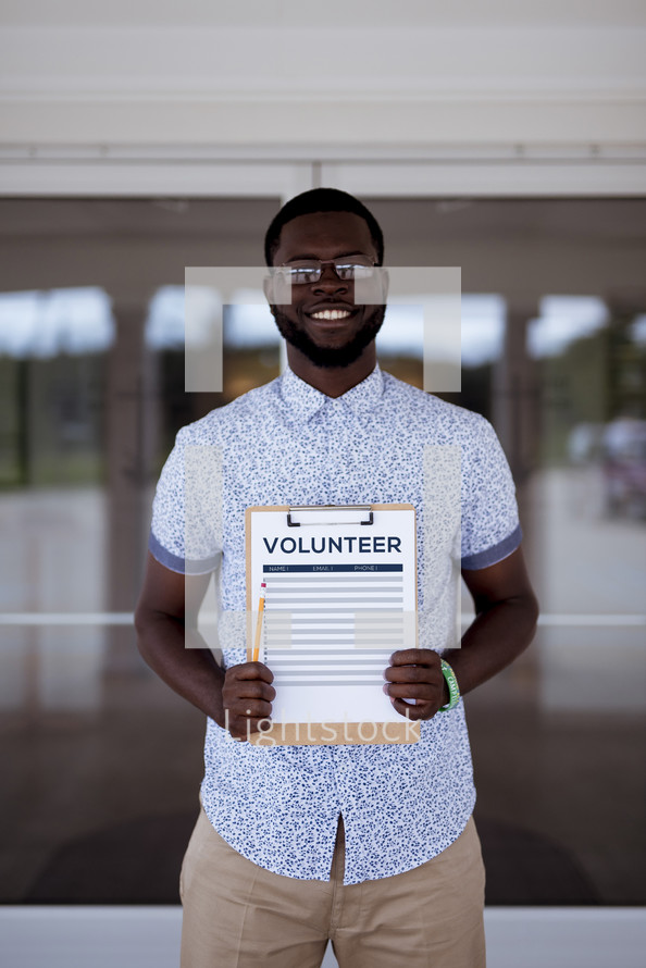 man holding a volunteer signup sheet on a clipboard 