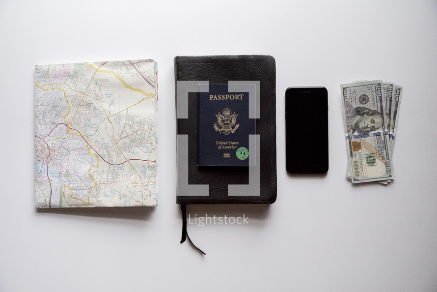 map, passport, Bible, cellphone, and cash on a white background 