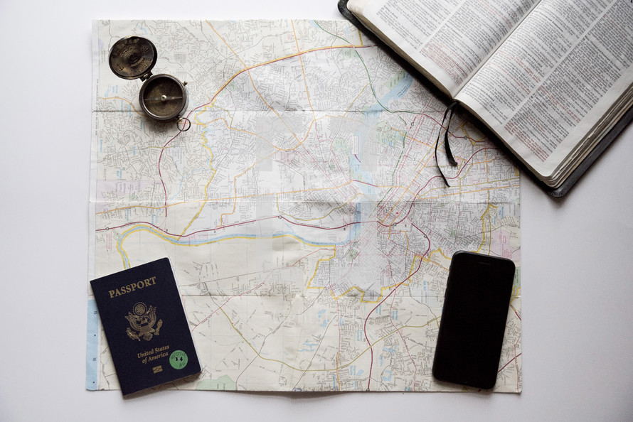 map, passport, Bible, cellphone, and compass on a white background 