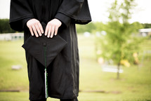 graduate holding a graduation cap 