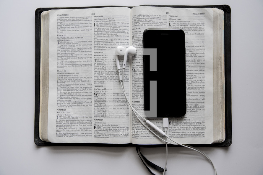phone, earbuds, and opened Bible 