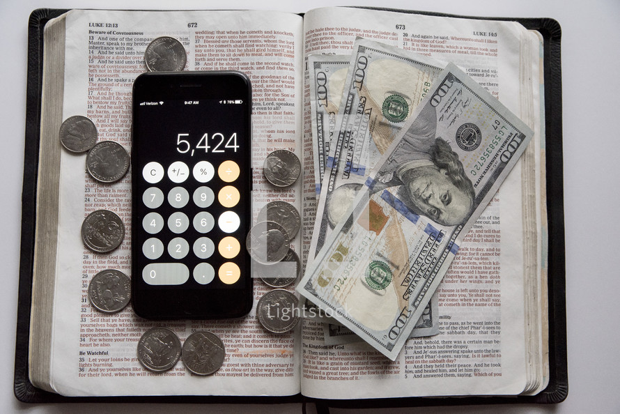 money, calculator app, on the page of a Bible 