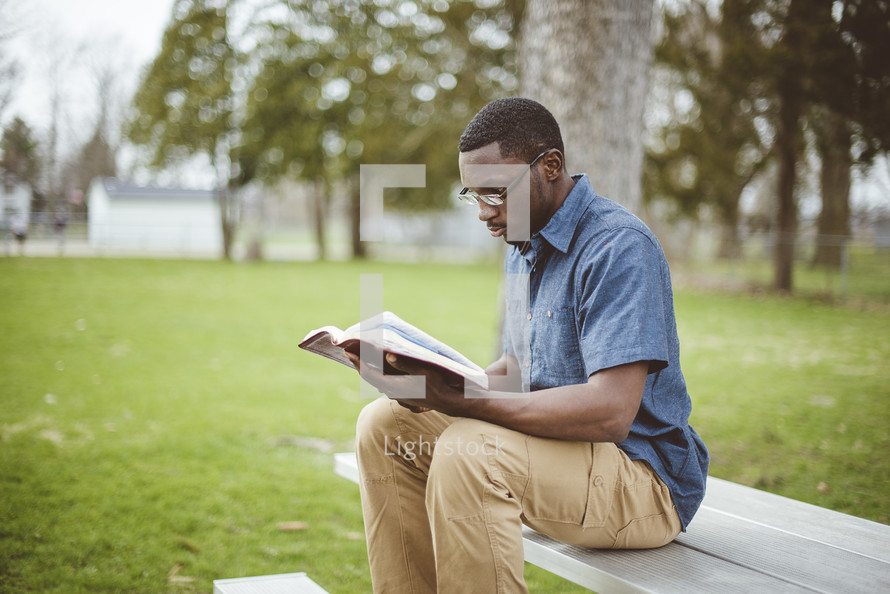 a man reading a Bible outdoors