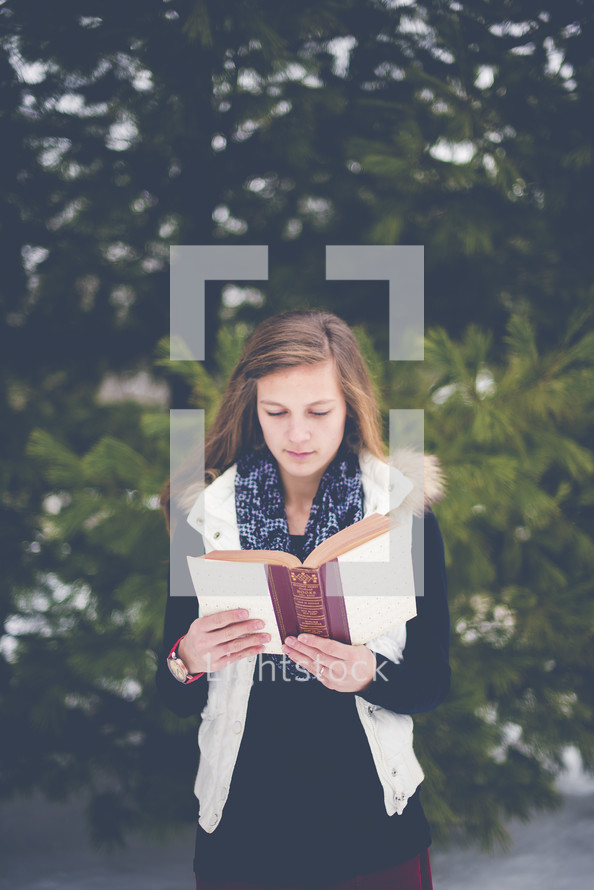 girl reading a Bible outdoors in winter 