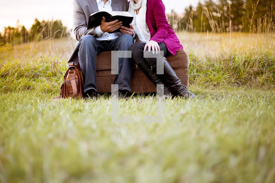 couple reading a Bible together outdoors 