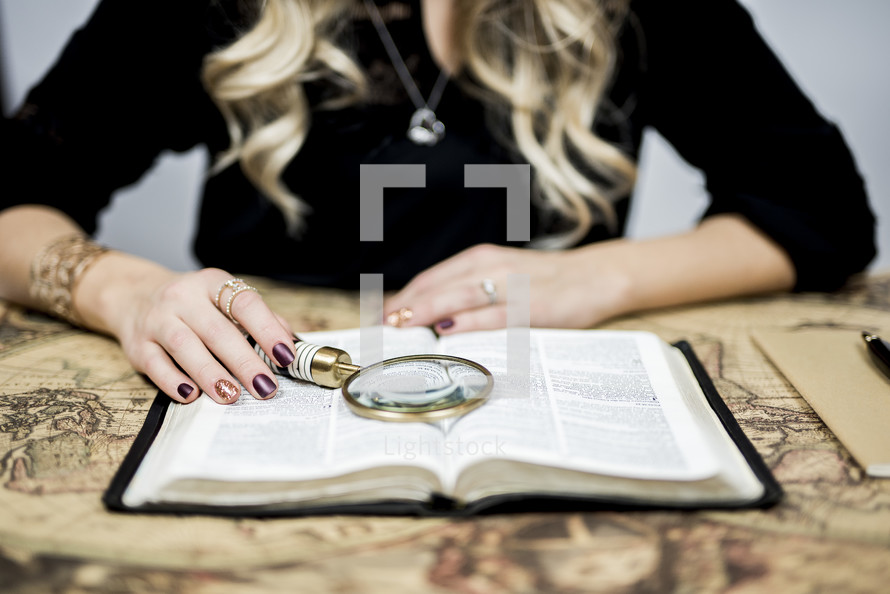woman reading a Bible with a magnifying glass 