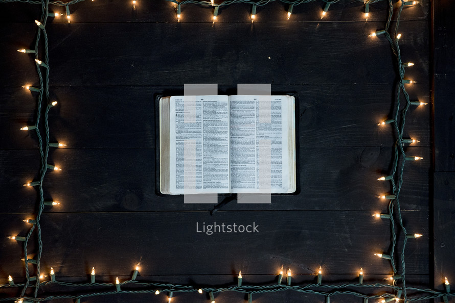 Pages of an opened Bible with Christmas lights border 