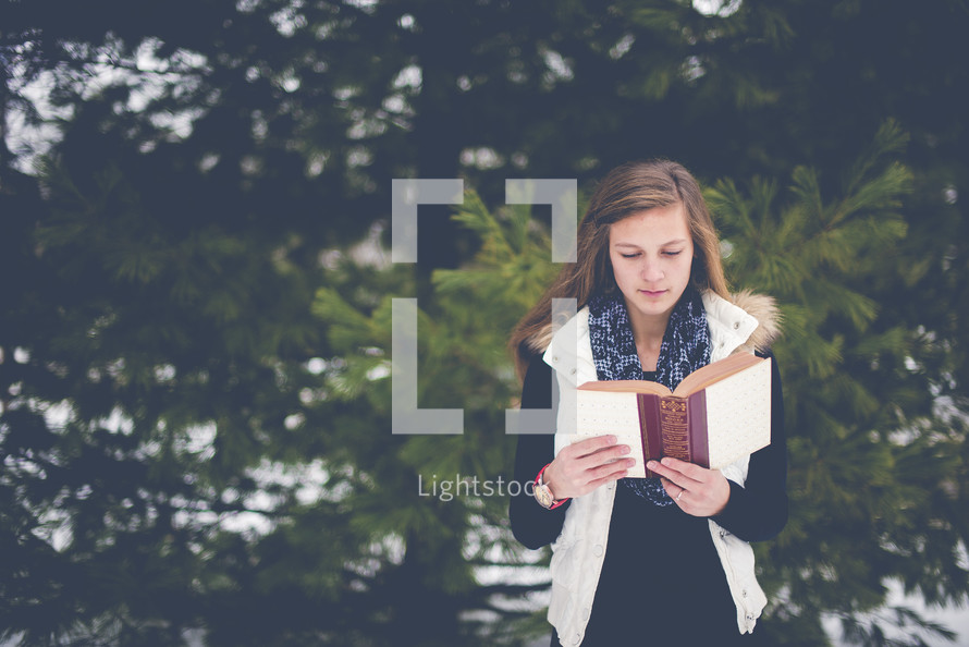 girl reading a Bible outdoors 