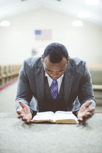 a man praying over a Bible in a church 