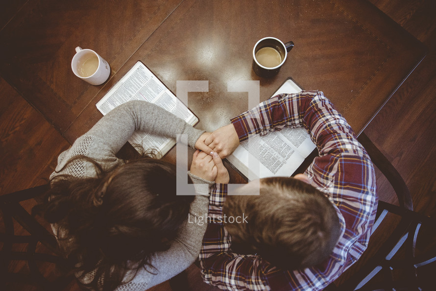 a couple holding hands reading Bibles 